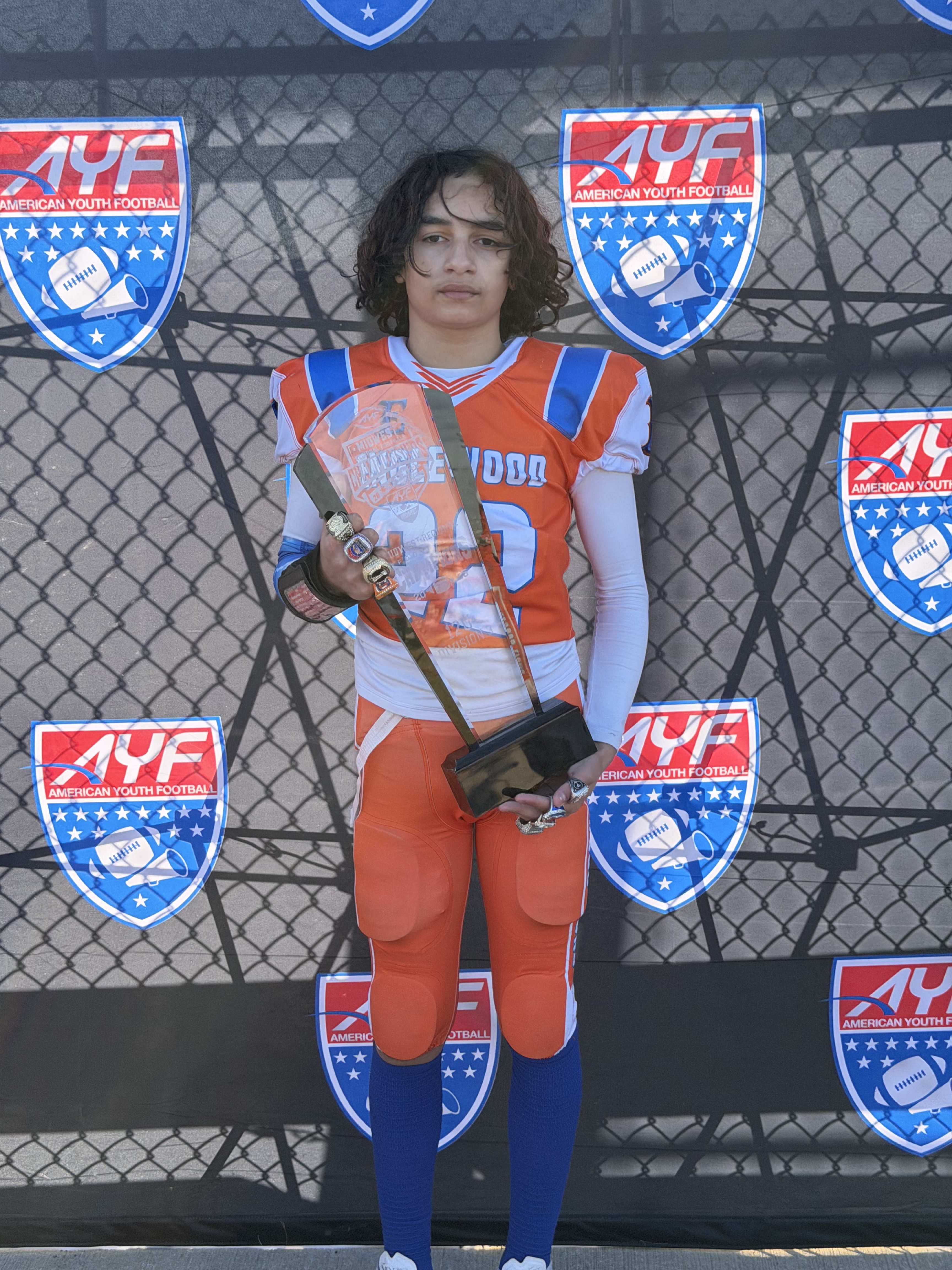 Denard Bell Jr. holding his football trophy in uniform